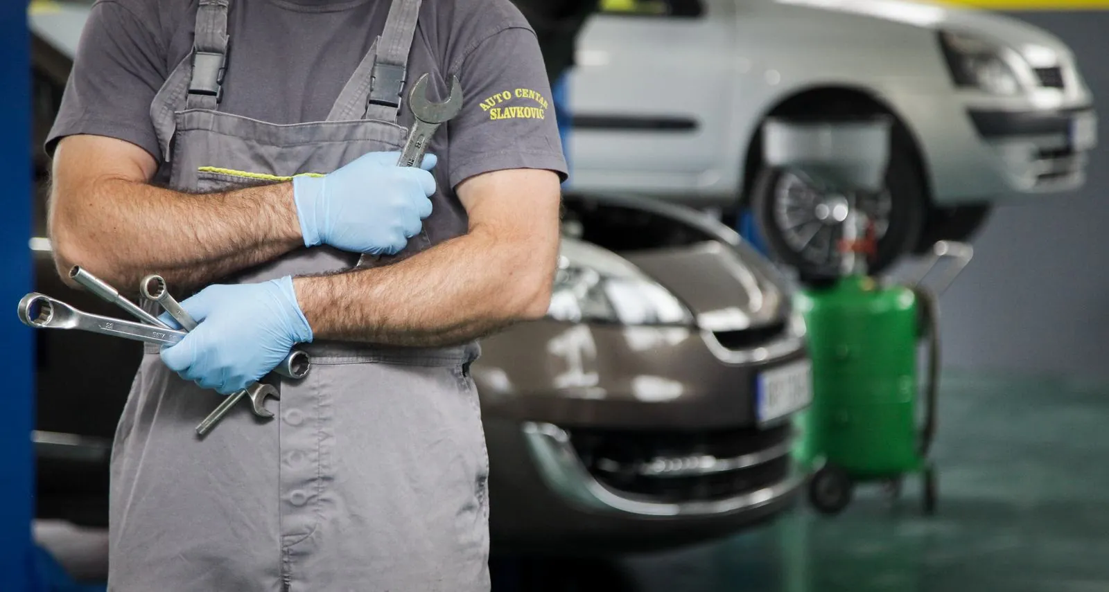Majstor u servisu Auto Centar Slavković radi ispod vozila podignutog na dizalici
